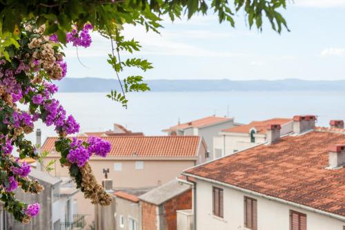 a city view from a tree with purple flowers at Apartments Leut 80m from the Sea in Podgora