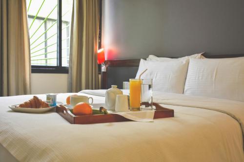ein Tablett mit Essen auf einem Bett in einem Hotelzimmer in der Unterkunft Ganalé Hôtel in Dakar