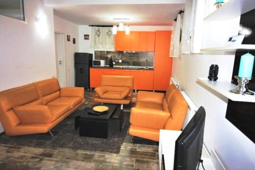 a living room with orange furniture and a kitchen at Maria*s Apartment! in Cristian