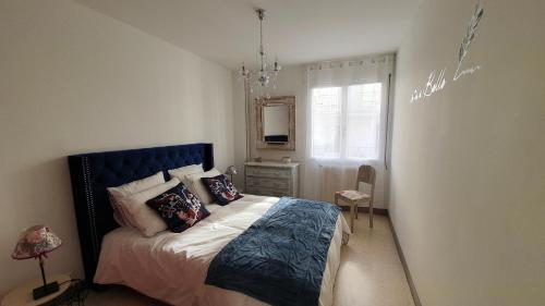 1 dormitorio con 1 cama con cabecero azul y espejo en Lovely Suite Nimes Romaine, en Nimes