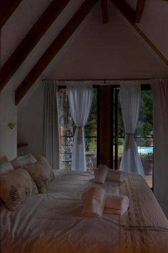 a large white bed with two windows in a bedroom at Linaje Hotel Boutique & Relax in Lago Puelo