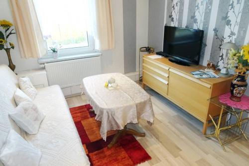 sala de estar con sofá blanco y TV en Ferienwohnung Dickes en Brandenburg