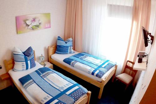 2 camas individuales en una habitación con ventana en Ferienwohnung Dickes en Brandenburg