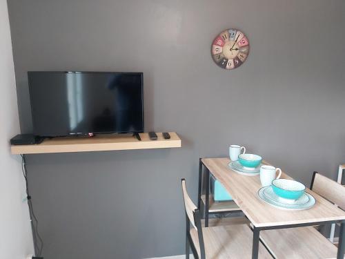 a dining room with a table with a tv and a clock at Hébergements Sylvain in Neuilly-lʼÉvêque