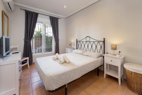 ein Schlafzimmer mit einem Bett mit weißen Laken und einem Fernseher in der Unterkunft Homes of Spain, Al Andalus Residencial Apartamento P bajo con WIFI in Playas de Vera