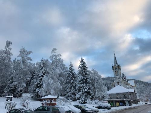 a church covered in snow with cars parked in front at Penzion Mája in Josefuv dul