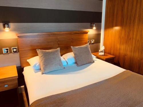 a bedroom with a large white bed with a wooden headboard at The Craibstone Suites in Aberdeen