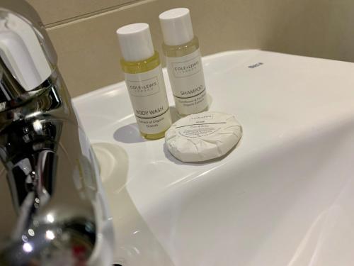 two bottles of moisturizers sitting on a bathroom sink at The Craibstone Suites in Aberdeen