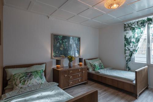 a bedroom with two beds and a dresser and a window at Gästezimmer im Dorfzentrum in Rothenthurm