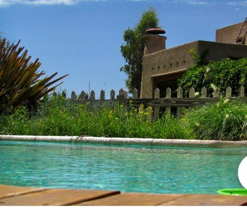 a swimming pool in front of a house at Exquisita habitación en suite en el corazón de Chacras de Coria in Chacras de Coria