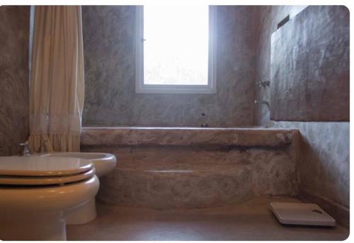 a bathroom with a tub and a toilet and a window at Exquisita habitación en suite en el corazón de Chacras de Coria in Chacras de Coria