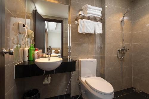 La salle de bains est pourvue de toilettes blanches et d'un lavabo. dans l'établissement An Phú Nguyễn Hoàng Hotel, à Hanoï