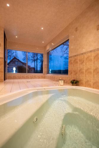 une grande baignoire dans une pièce avec une grande fenêtre dans l'établissement Clos Celeste - campagne d Etretat avec piscine et spa, à Étretat
