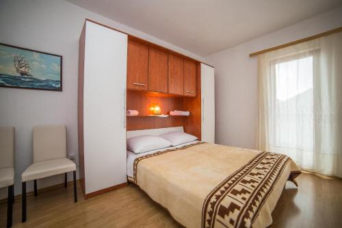 1 dormitorio con 1 cama, 1 silla y 1 ventana en Apartments Brižić, en Bol