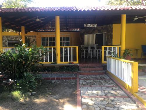 une maison jaune avec un portail et une terrasse couverte dans l'établissement Villa Ana, à Pajarito