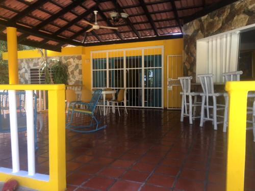 a living room with yellow walls and white chairs at Villa Ana in Pajarito