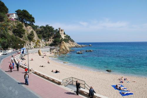 a beach with people on the sand and the ocean at Hotel Rosamar Maxim 4*- Adults Only in Lloret de Mar