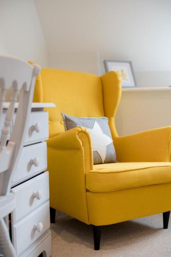a yellow chair with a pillow next to a dresser at The Red Lion at Hellidon in Daventry