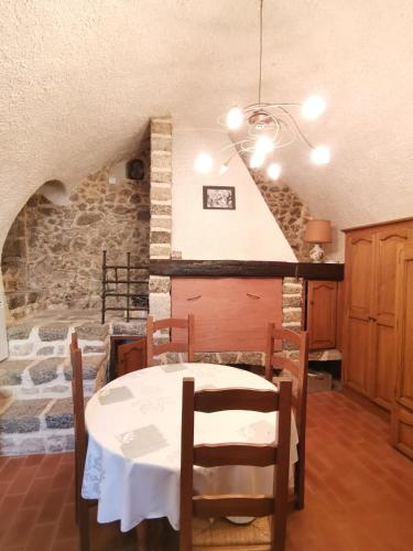 une salle à manger avec une table et un mur en pierre dans l'établissement Chez Gilles Math, à Saint-Martin-de-Brômes