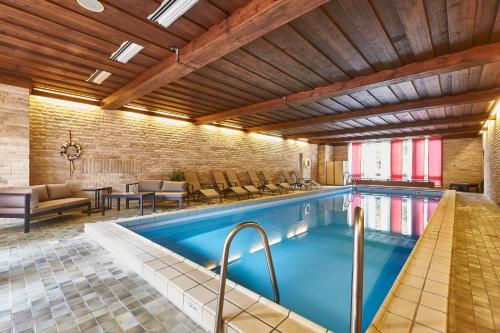 an indoor pool with chairs and a table at Flair Hotel Dobrachtal in Kulmbach