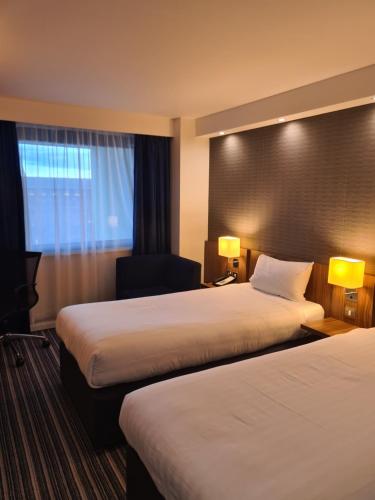 a hotel room with two beds and a chair at Holiday Inn Express Middlesbrough - Centre Square by IHG in Middlesbrough
