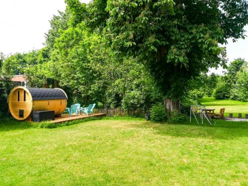 a yard with a large tree and a wooden house at Skindles Guesthouse in Poperinge