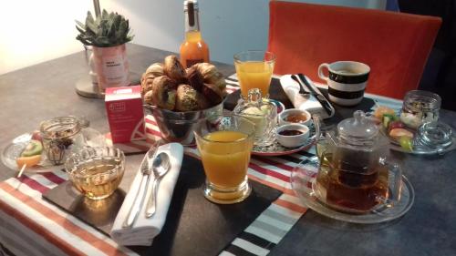 - une table avec un petit-déjeuner composé de jus de fruits et de boissons dans l'établissement B&B au Moulin de Riottier, à Jayat