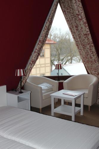 a bedroom with a bed and two chairs and a table at Hotel Zum Gondoliere in Oranienbaum-Wörlitz