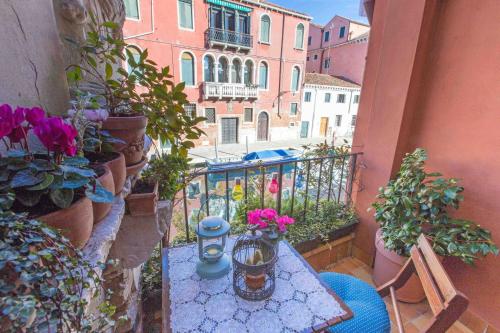 a small table on a balcony with flowers on it at CA CAMMELLO private terrace and canal view in Venice