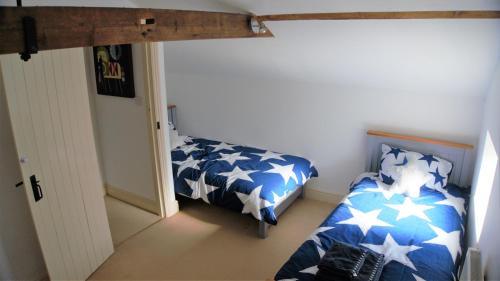 um quarto com uma cama com lençóis azuis e brancos em The Coach House em Hawkhurst