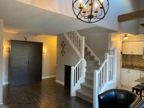 a living room with a staircase and a chandelier at Blue Mountain 2 Story Studio Loft in Blue Mountains