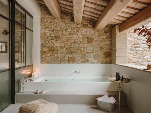 bañera en una habitación con pared de piedra en Mas Generós - Adults-Only Eco Hotel, en Fonteta