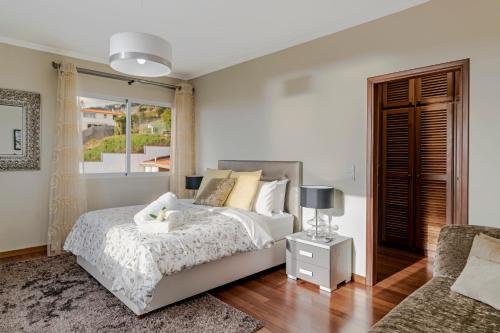 een witte slaapkamer met een bed en een raam bij Exquisite Madeira Villa Villa Funchal Belair 4 Bedroom Panoramic Sea View Heated Pool Hot in Funchal