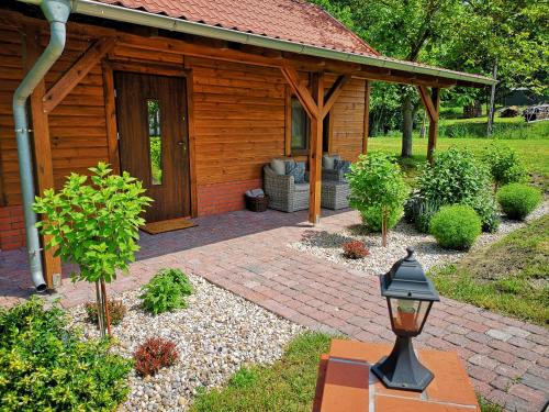 a wooden cabin with a brick patio in front of it at Dom dla dwojga w Starym Młynie w Brzeźnicy in Brzeźnica