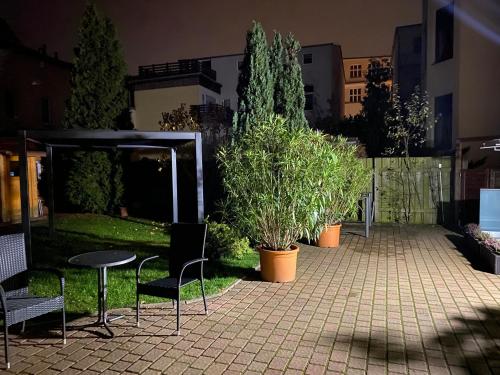 a patio with a table and chairs and trees at Pension Villa Ostseetraum in Warnemünde