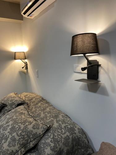 1 dormitorio con 1 cama y 2 lámparas en la pared en Leguizamon Studios & Suites Premium en Salta