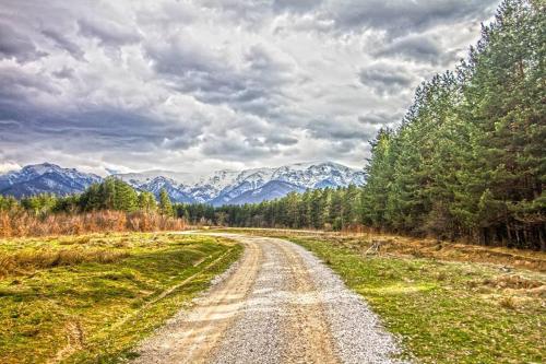 a dirt road in the middle of a field with mountains at Къща за гости "Край Реките" in Apriltsi