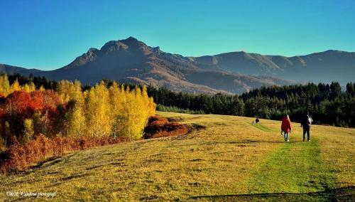 two people walking down a hill with mountains in the background at Къща за гости "Край Реките" in Apriltsi
