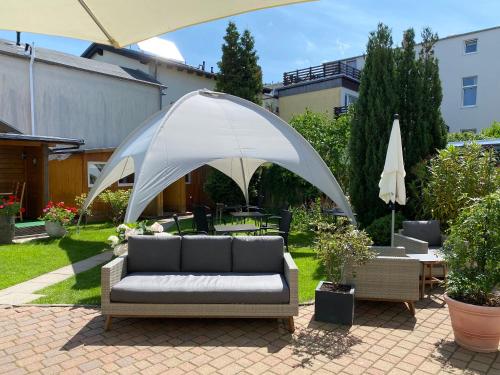 Pension Villa Ostseetraum في فارنمونده: أريكة تحت مظلة بيضاء في الفناء