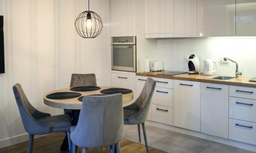a kitchen with a table and chairs in a kitchen at Apartament Jelitkowski Dwór in Zaspa