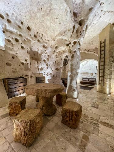 a stone room with a table and some logs at La Suite Nella Roccia in Matera