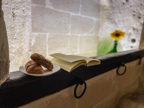 une assiette de pâtisseries et un livre sur une étagère dans l'établissement La Suite Nella Roccia, à Matera