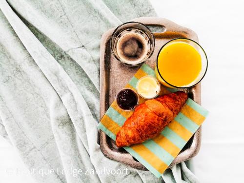 a plate of food with fish and a glass of orange juice at Boutique Lodge Zandvoort in Zandvoort