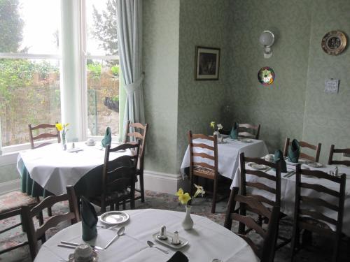 uma sala de jantar com mesas e cadeiras e uma janela em Bron Orme Private Hotel em Llandudno