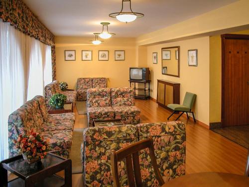 a living room with a couch and chairs and a tv at Hotel Isolino in O Grove