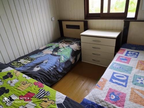 ein Schlafzimmer mit 2 Betten und einer Kommode darin in der Unterkunft Casa de Praia. Lugar sossegado para recarregar as energias. in Passo de Torres