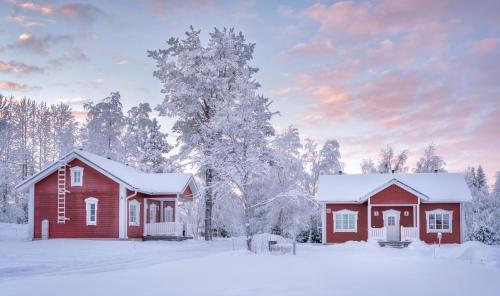 een rood huis in de sneeuw met bomen bij Kukkolankoski Resort - Vierastalot in Kukkola
