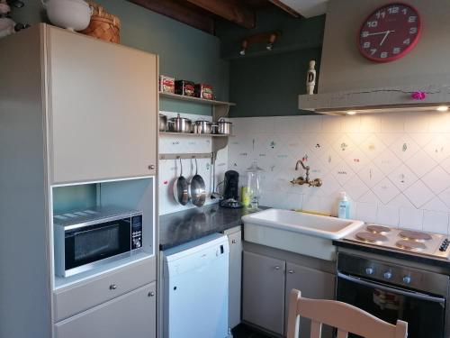 eine Küche mit Mikrowelle und Spüle in der Unterkunft L'autre rive de la Tourelle in Ways
