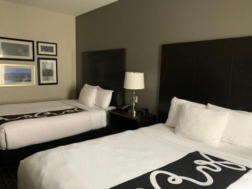 a hotel room with two beds with white sheets at La Quinta by Wyndham Billings in Billings