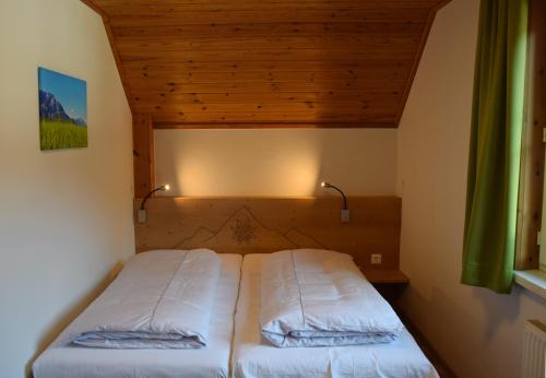 a bed in a bedroom with a wooden ceiling at Alpenvereinshaus Pruggern in Pruggern